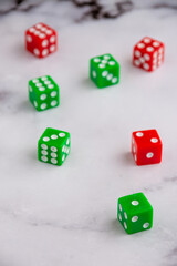 Top view of green and red dice on white marble, selective focus, vertical, with copy space