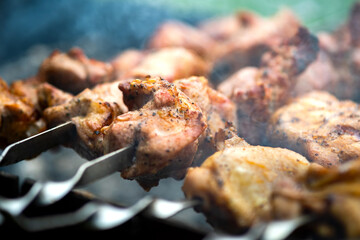 Shashlik or shish kebab preparing on barbecue grill over hot charcoal. Grilled pieces of pork meat on metal skewers.
