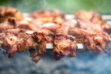 Shashlik or shish kebab preparing on barbecue grill over hot charcoal. Grilled pieces of pork meat on metal skewers.
