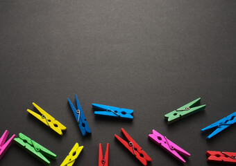 Mini colorful wooden craft pegs flat lay on black dark grunge texture pattern abstract background. Free space for your design. Top view, no people, horizontal image style.