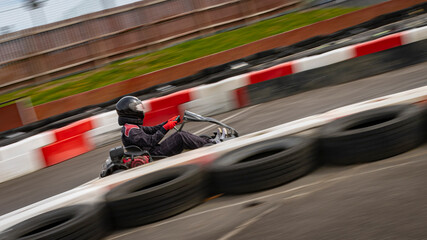 A panning shot of a racing kart as it circuits a track. - obrazy, fototapety, plakaty