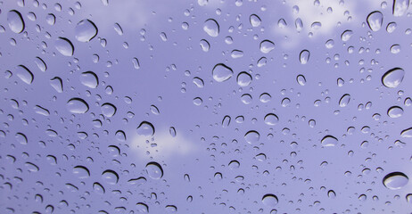 Rain drops cling to the car windows on a rainy day Blurred background blue sky