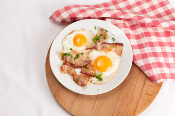 Fried eggs with bacon on a white plate