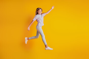 Fototapeta na wymiar Cheerful sporty girl jumping running isolated over yellow background