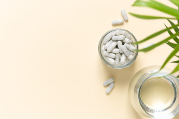 Collagen pills and a glass of water on a beige background with a copy space. Extra protein intake