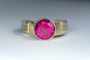 Vintage USSR gilded, gold plated 873 silver womens ring with round lab created crimson red ruby corundum faceted gemstone in a blind setting. Front view, gray gradient background. Close-up, macro.