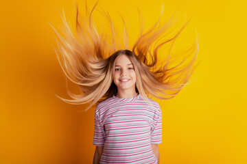 Photo of happy little girl with blonde hair flying isolated on yellow background