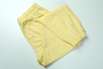 Fototapeta na wymiar Folded yellow sweatpants on white background, top view