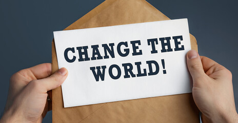 Closeup of a male hands holding craft envelope with text Change the world on blue background