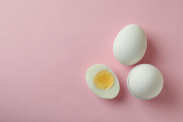 Tasty boiled eggs on pink background, space for text