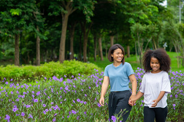 Happy mixed race family in park. Mother with little daughter holding hand and walking together in...