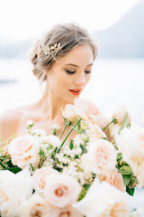 Smiling bride with a bouquet of flowers stands on the shore of Lake Como