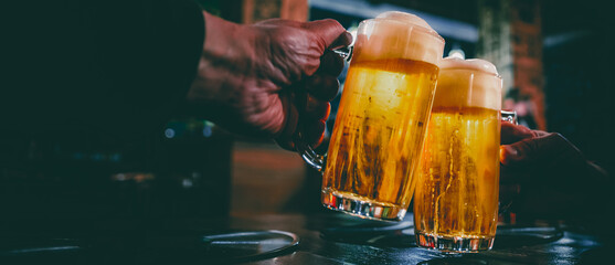 Close-up view of a two glass of beer in hand. Beer glasses clinking in bar or pub