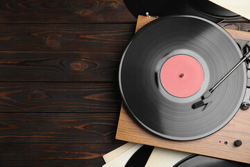 Modern player and vinyl records on wooden background, flat lay. Space for text