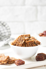 Coconut cookies with dates and carrots in a white bowl on a light background close-up. The concept of a healthy snack no sugar	