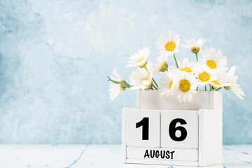cube calendar for August with daisy flowers over blue