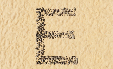 Concept or conceptual stones on beach sand handmade symbol shape, golden sandy background, sign of E. 3d illustration metaphor for education, nature, summer, sunny, seaside and tropical