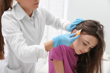 Doctor using nit comb on little girl's hair indoors. Anti lice treatment