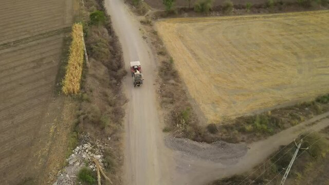 Aerial view large tractor cultivating a dry field. Top down aerial view tractor cultivating ground and seeding a dry field. Aerial tractor cuts furrows in farm field for sowing