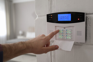 Man entering code on security alarm system at home, closeup