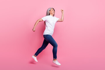 Full length body size view of lovely cheerful grey-haired woman jumping running isolated over pink pastel color background