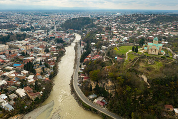 Scenic aerial view of Kutaisi cityscape on banks of Rioni River in spring overlooking medieval Bagrati Cathedral, Imereti region, Georgia.