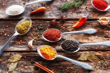 spices in tablespoons and herbs on a wooden background close-up