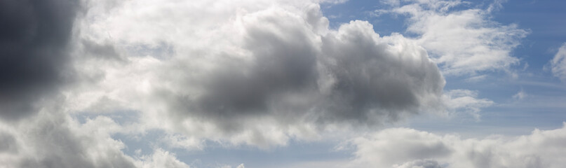 Panorama with well defined cumulus cloud chased by dramatic dark rain filled front in dramatic sky scenery landscape. Weather conditions and climate concept. Science backdrop.