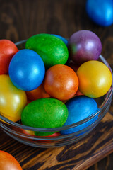 Fototapeta na wymiar Colored Easter eggs in bowl of glass on an old wooden table