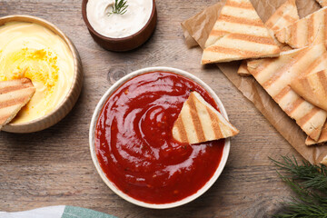 Sauce and pita chips on wooden table, flat lay