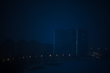 Night city on a background of fog. Thick blue fog in a dark, scary evening city. Magic and...