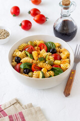 Pasta salad with tomatoes, zucchini, olives and spinach. Healthy eating. Vegetarian food.