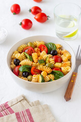 Pasta salad with tomatoes, zucchini, olives and spinach. Healthy eating. Vegetarian food.