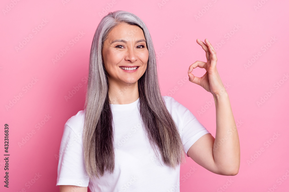 Wall mural portrait of attractive cheerful woman showing ok-sign ad advert trust isolated over pink pastel colo