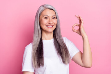 Portrait of attractive cheerful woman showing ok-sign ad advert trust isolated over pink pastel...