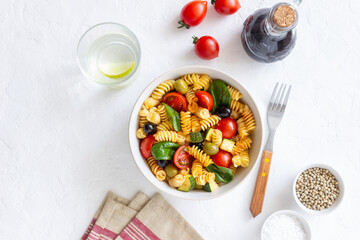 Pasta salad with tomatoes, zucchini, olives and spinach. Healthy eating. Vegetarian food.