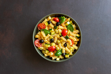Pasta salad with tomatoes, zucchini, olives and spinach. Healthy eating. Vegetarian food.