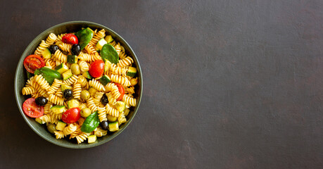 Pasta salad with tomatoes, zucchini, olives and spinach. Healthy eating. Vegetarian food.