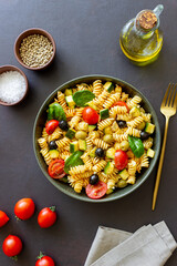 Pasta salad with tomatoes, zucchini, olives and spinach. Healthy eating. Vegetarian food.
