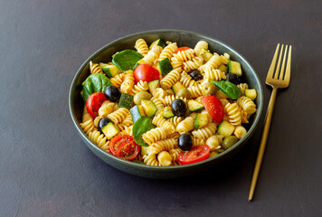 Pasta salad with tomatoes, zucchini, olives and spinach. Healthy eating. Vegetarian food.