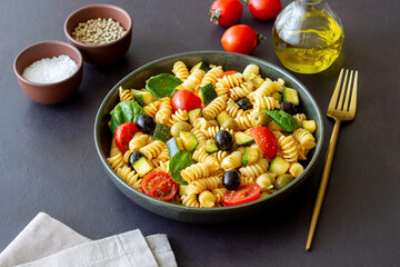 Pasta salad with tomatoes, zucchini, olives and spinach. Healthy eating. Vegetarian food.