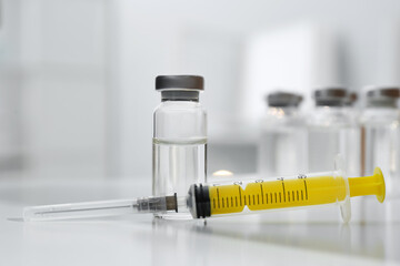 Syringe and vial of medicine on white table, closeup