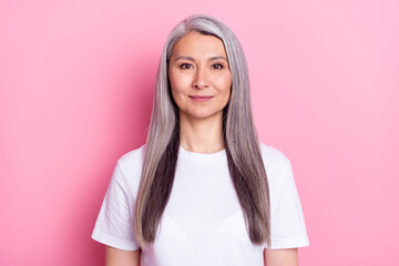 Photo portrait of elder woman smiling in white t-shirt isolated on pastel pink color background