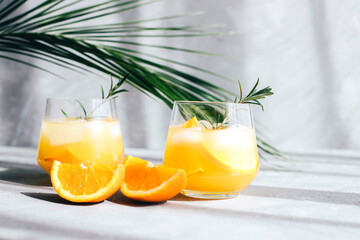 Cocktails with orange slices in glass glasses under the branches of palm trees. Summer drinks....