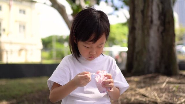 Asian chinese child girl eating ice cream hungrily for the first time