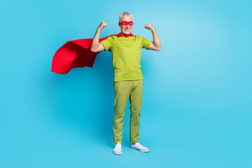 Full length body size view of handsome cheery grey-haired superhero showing arms strength isolated over bright blue color background