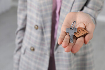 Real estate agent holding key indoors, closeup