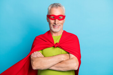 Portrait of handsome strong cheerful grey-haired superman folded arms isolated over bright blue color background