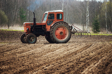 a tractor plows a field. preparation of agricultural land for planting. a mechanical plow makes...