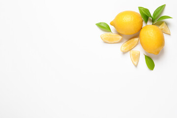 Whole and cut lemons with leaves on white background, top view